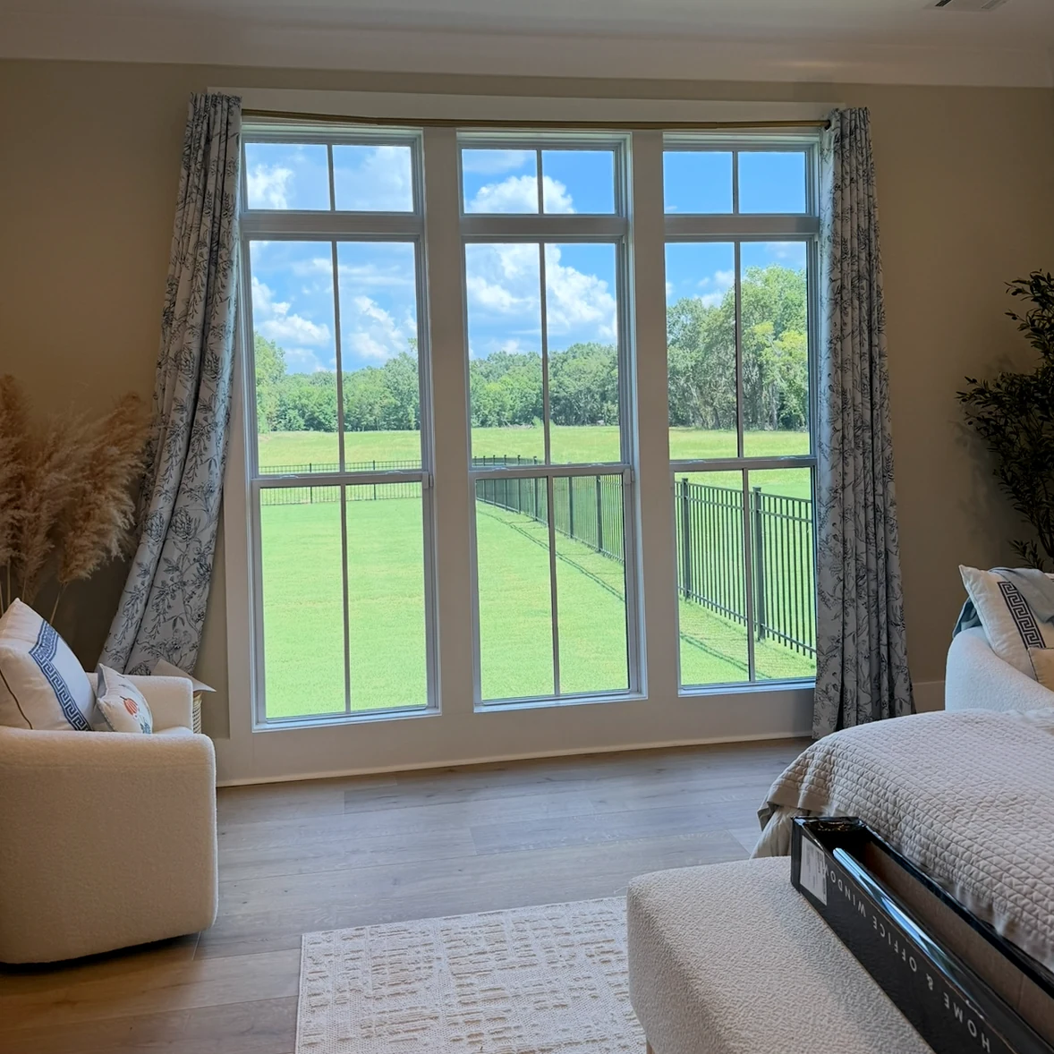 Three tall residential windows overlooking a lawn and trees